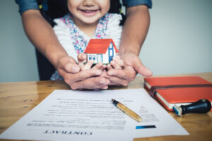 hands holding small house after signing contract